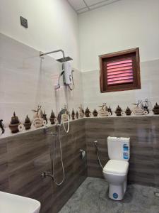 a bathroom with a shower and a toilet and a sink at Muthugala Resort in Anuradhapura +5 photos