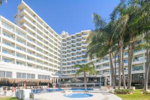 an apartment building with a pool and palm trees at Hotel Parasol by Dorobe in Torremolinos