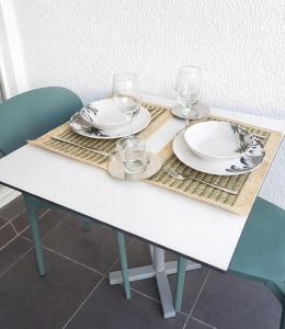 a white table with two plates and glasses on it at Studio LY'S in Saint-François