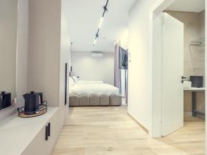 a white bedroom with a bed and a hallway at Enigma Rooms in Lezhë
