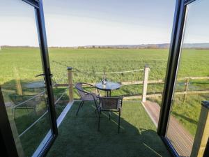 a balcony with a table and chairs and a view of a field at GiGi's Horsebox in Evesham