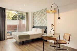 a bedroom with a bed and a table and a chair at PARK SEDO Aparthotel in Rubí