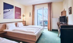 a bedroom with a bed and a tv and a window at Hotel Kirchboden by Alpeffect Hotels in Wagrain +57 photos