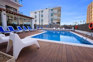 ein Swimmingpool auf einem Deck mit Stühlen und einem Gebäude in der Unterkunft Adia Hotel Cunit Playa in Cunit