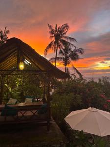 an umbrella and a table with a sunset in the background at Lombok Coconut Hotel in Mangsit