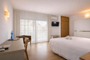 ein Hotelzimmer mit einem weißen Bett und einem Schreibtisch in der Unterkunft Adia Hotel Cunit Playa in Cunit + 23 Fotos