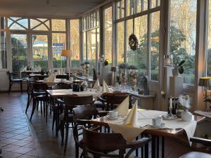 a restaurant with tables and chairs and windows at Strandhotel Sonnenburg by ANS in Kühlungsborn