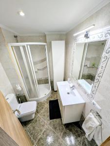 a bathroom with a sink and a toilet and a mirror at Casa Belice Huelva in Huelva