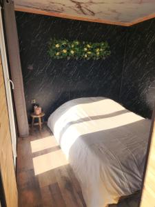 a bed in a room with a black wall at Le Nid Douillet du Tacot in Le Thillot