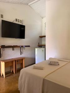 a room with a table and a television on a wall at Pousada Embaubas in Serra do Cipo