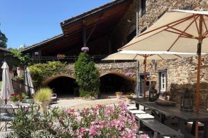 a patio with a table and an umbrella and flowers at Domaine de Maples in Dore-lʼÉglise