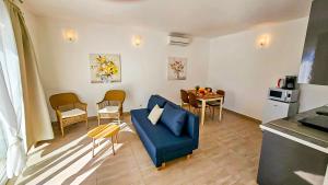 a living room with a blue couch and a table at Beach front with Swimming pool, Illyria Resort Apt 101 in Milna