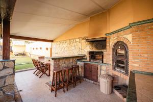 a patio with an outdoor kitchen with bar stools at Villa Oropéndola para familias, a pocos minutos de Granada, Piscina agua salada, Parking privado, Barbacoa, Chimenea, 14 pax in Belicena