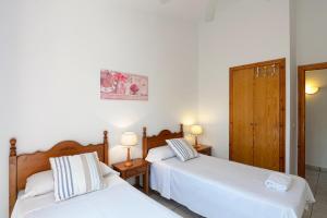two beds in a room with white walls and two lamps at Villa Flor by 3VILLAS in Cala en Bosc +5 photos