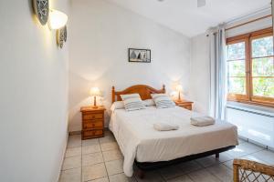 a bedroom with a bed with two night stands and a window at Villa Flor by 3VILLAS in Cala en Bosc