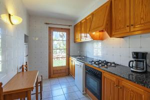a kitchen with wooden cabinets and a stove top oven at Villa Flor by 3VILLAS in Cala en Bosc