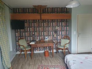 a room with a desk and chairs and a wall of books at Chambre d'hôtes Le Luquet in Chazelles