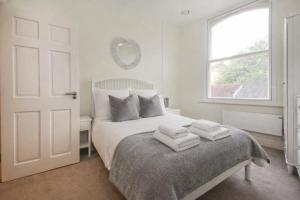 a white bedroom with a bed with towels on it at Minster's Keep- Near York Minster & Free Parking in York