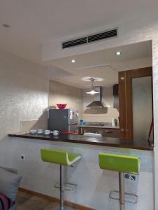 a kitchen with a counter and two green bar stools at Tanger City 5 in Tangier