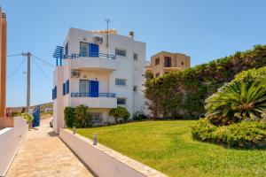 a white house with blue windows and a green yard at The Marina View in Lavrio