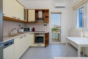 a kitchen with white cabinets and a sink and a window at The Marina View in Lavrio