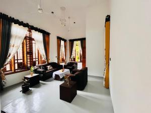 a living room with couches and tables and windows at Coral Bay Villa in Pottuvil