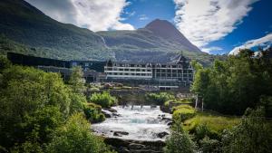 a hotel with a river in front of a mountain at Hotel Union Geiranger Resort & Spa in Geiranger