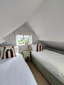 two beds in a attic room with a window at The Pack Horse Exmoor National Park Allerford Riverside Cottage & Apartments in Minehead
