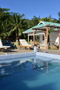 a swimming pool with two chairs and a house at Belle Vacance in Grand Anse