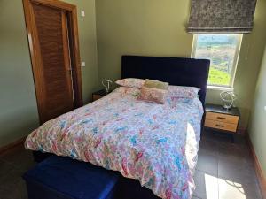a bedroom with a bed with a colorful comforter and a window at Suaimhneas in Lahinch