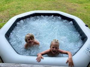 two children are swimming in a pool of water at Drentse Sleutels 6 persoons huisje met jacuzzi in Erm