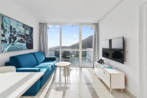 a living room with a blue couch and a large window at Mariposa del Sol in Patalavaca
