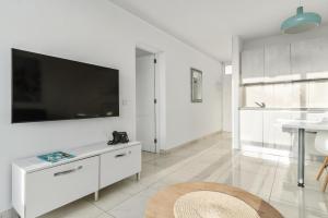 a white living room with a flat screen tv on the wall at Mariposa del Sol in Patalavaca