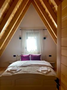 a bedroom with a bed with purple pillows and a window at Vila Ramonda in Žabljak