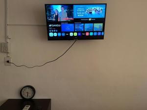 a flat screen tv hanging on a wall with a clock at Cómodo departamento en el corazón de Cancún in Cancún