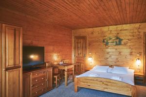 a bedroom with a bed with a television and a table at Penzion pod Šerákem - celý objekt Ostružná - Jeseníky in Ostružná