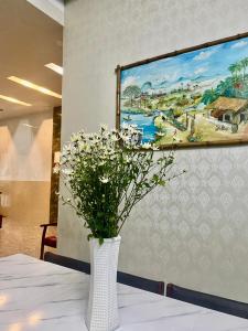 a vase with flowers on a table with a painting at Kavy Homestay in Thôn Trường Giang +56 photos