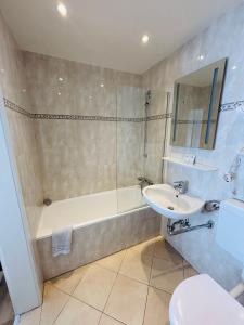 a bathroom with a sink and a tub and a toilet at Hotel Europa Pforzheim in Pforzheim +42 photos