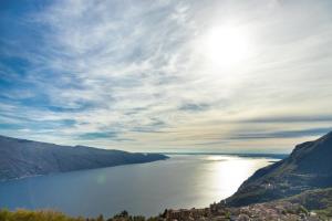 a view of a large body of water with the sun at Hotel Residence Panorama La Forca, GTSGroup in Tignale