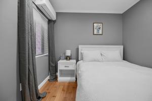 ein weißes Schlafzimmer mit einem Bett und einem Fenster in der Unterkunft Airport Subway Condo in Boston
