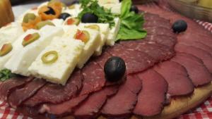 a plate of cured meat with cheese and olives at Rafting Camp Encijan in Foča