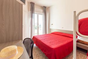 a bedroom with a bed and a table with a redspread at Hotel Sorriso in Misano Adriatico