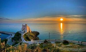 a sunset over a body of water with a lighthouse at Sperlonga Tiny Room in Sperlonga