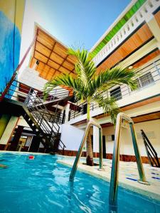 a pool with a palm tree in front of a building at Hotel Coralite Suites Santa Marta in Santa Marta