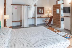 a bedroom with a white bed and a desk at Reve Island Lodge in Grand Anse