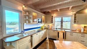 a kitchen with white cabinets and a sink and two windows at Penthouse Meeresrauschen in Dierhagen