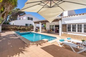 a pool with an umbrella and chairs and a house at Casa Masi by 3VILLAS in Son Parc