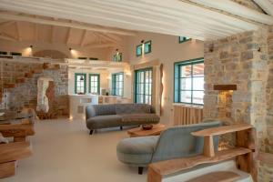 a living room with a couch and a stone wall at Cypresses Villas in Áno Gatzéa