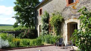 a stone house with a chair in the garden at La Colombière in Lurcy-le-Bourg