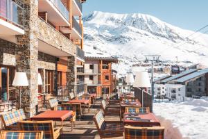 a balcony with tables and chairs and a mountain at Hôtel Daria-I Nor by Les Etincelles in L'Alpe-d'Huez